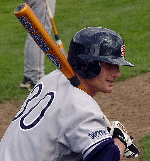 Joey Myers kneeling in the on-deck circle at Fresno State wearing a batting helmet