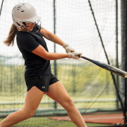 Softball hitter working through softball hitting drills in batting cage — swing flaw correction drills for youth and high school players