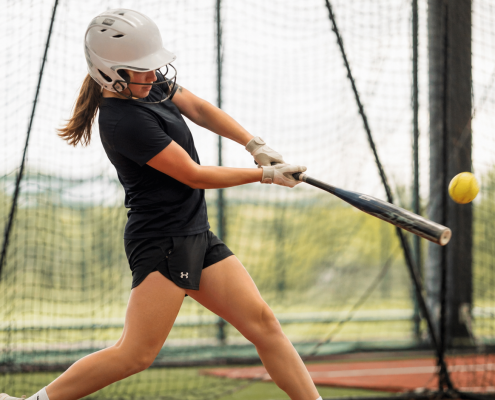 Softball hitter working through softball hitting drills in batting cage — swing flaw correction drills for youth and high school players
