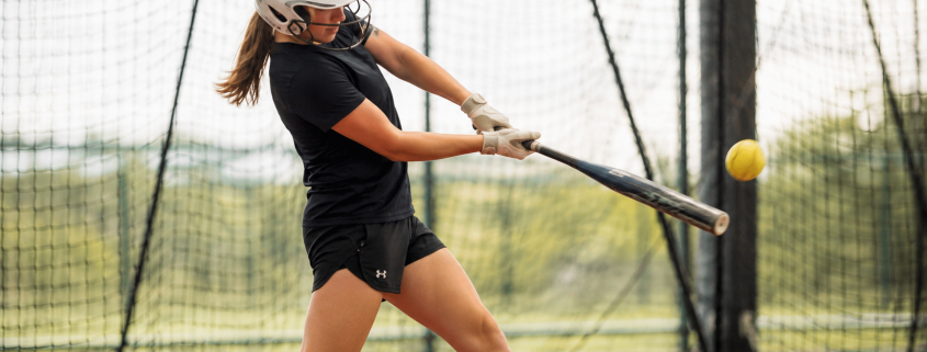 Softball hitter working through softball hitting drills in batting cage — swing flaw correction drills for youth and high school players