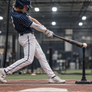 Youth baseball hitter front leg fully braced at impact — demonstrating the blocking position in batting cage
