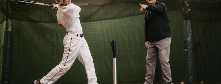 Youth baseball player at the tee with coach — baseball hitting lessons for swing mechanics