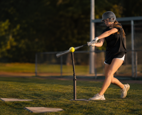 Softball player hitting off a tee with overload bat — softball hitting drills for swing mechanics