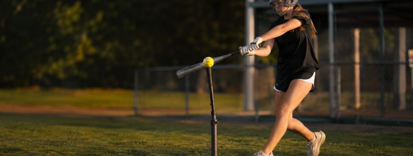 Softball player hitting off a tee with overload bat — softball hitting drills for swing mechanics