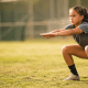 Youth softball player doing bodyweight squat at practice - youth softball workout plan for girls ages 10–14